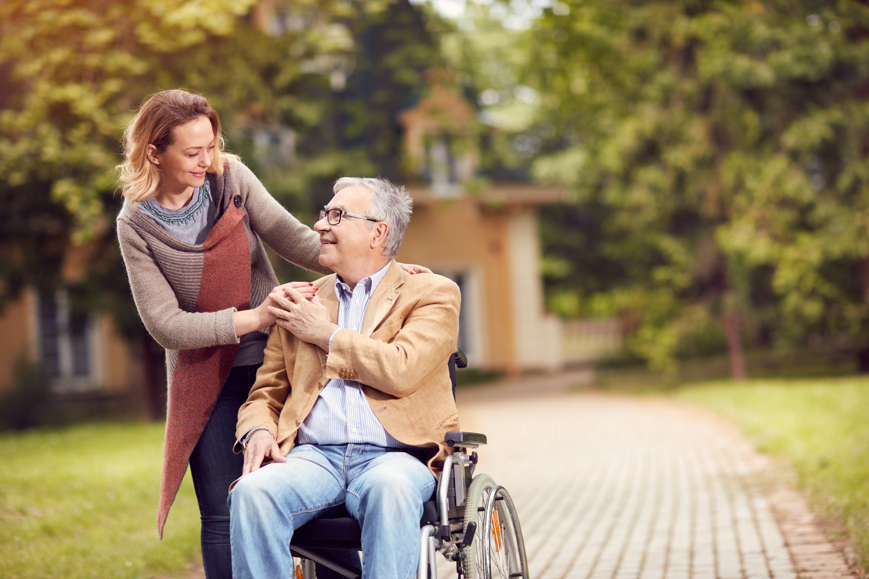 senior man in wheelchair with happy caregiver daughter